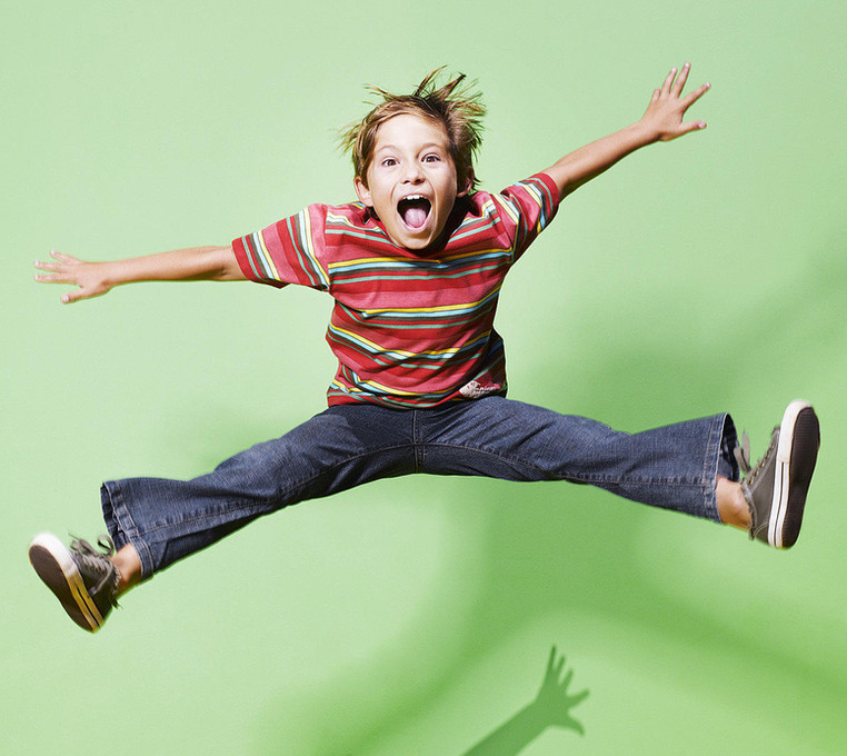 Child jumping joyfully against a green background
