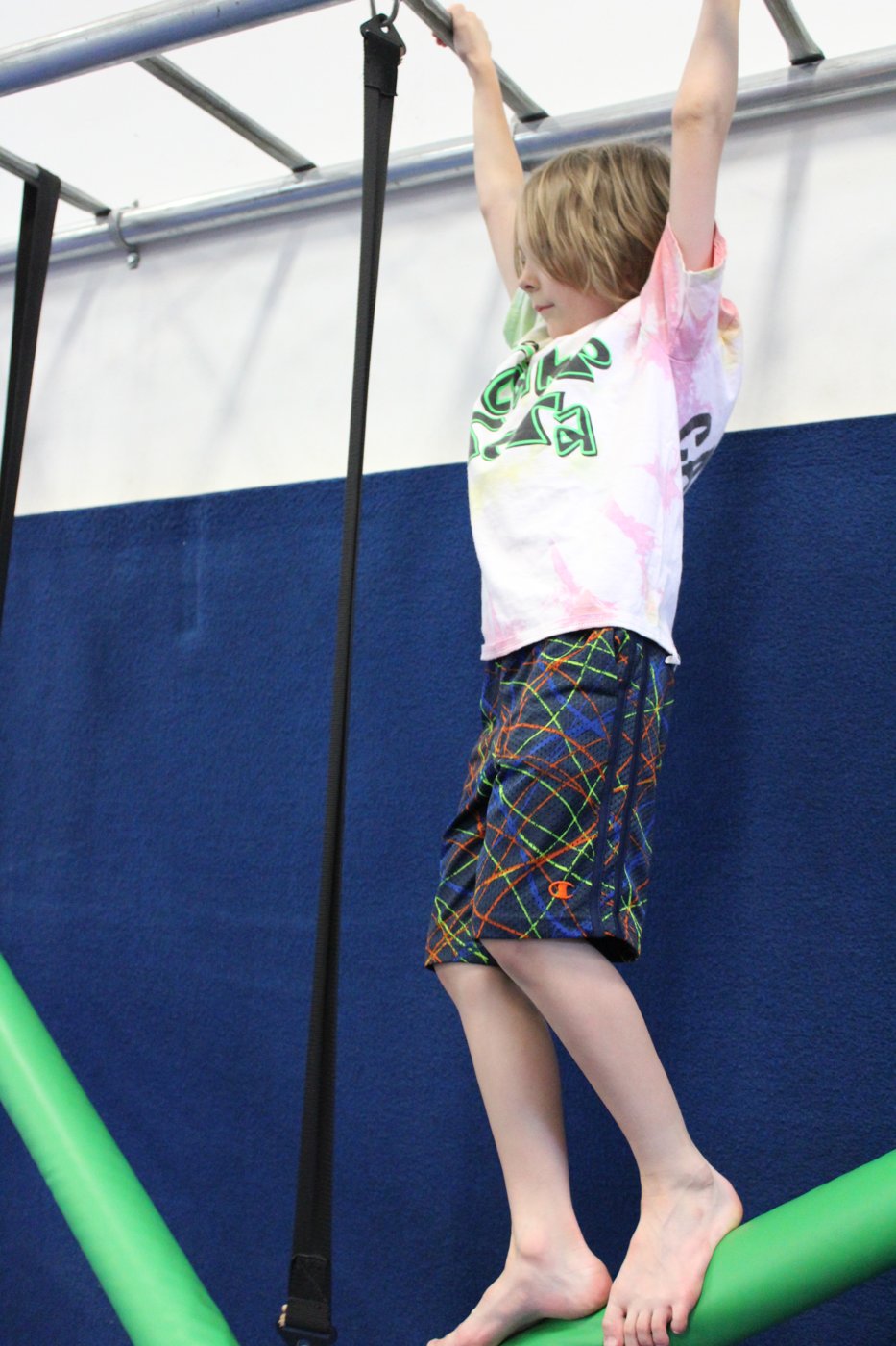 Child hanging from a bar above a foam roller